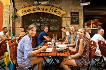 Locals are eager to share their culture with an approachable traveler, such as at this “meet-up” dinner in Nice, France. Photo by Dominic Arizona Bonuccelli